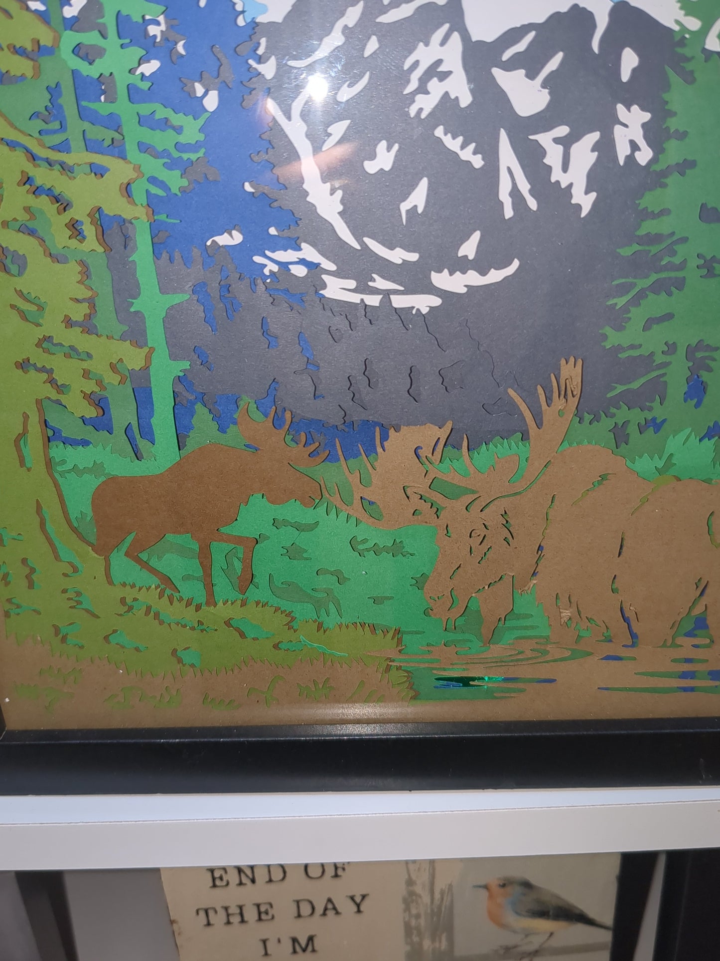 8 x 10” black shadow box with paper cut moose in mountain scene with lights